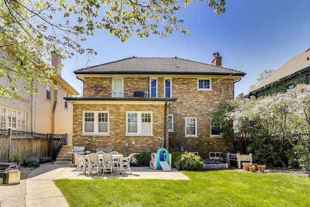 back of house with a chimney, a patio, and brick siding