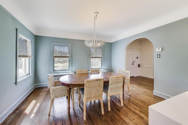 dining room with a chandelier, healthy amount of natural light, wood finished floors, and arched walkways