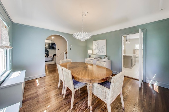 dining area featuring arched walkways, a chandelier, healthy amount of natural light, and wood finished floors
