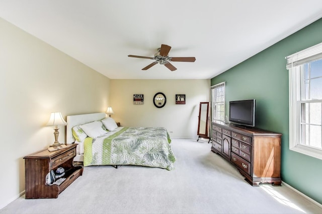 carpeted bedroom featuring multiple windows, baseboards, and a ceiling fan