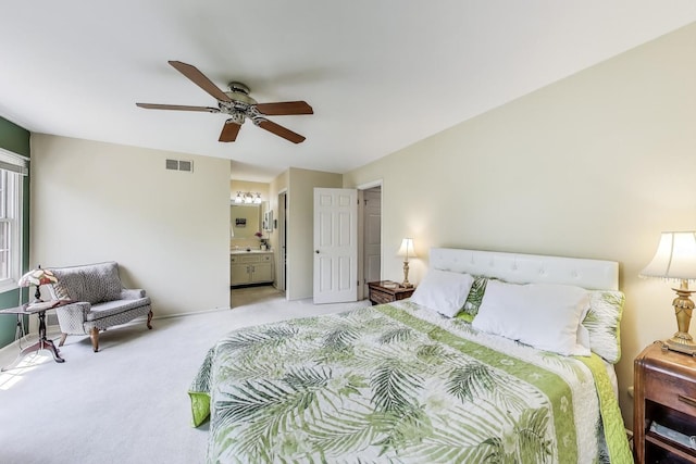 bedroom featuring light colored carpet, ensuite bathroom, a ceiling fan, and baseboards