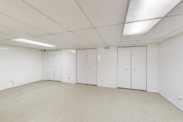 finished basement featuring a paneled ceiling and baseboards