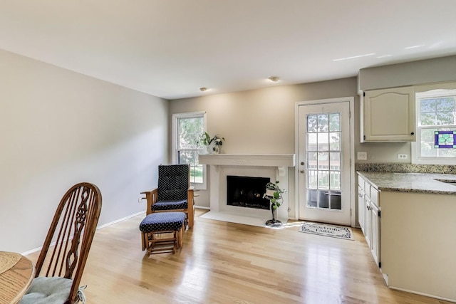 kitchen with light wood-style floors, light stone countertops, a fireplace with flush hearth, and baseboards