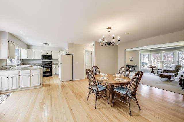 dining room featuring a chandelier, plenty of natural light, and light wood finished floors