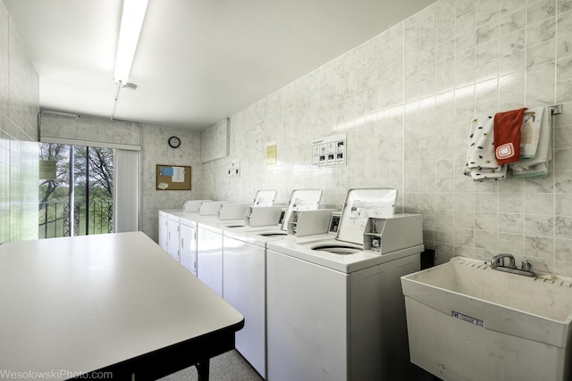 communal laundry room with washing machine and clothes dryer and tile walls
