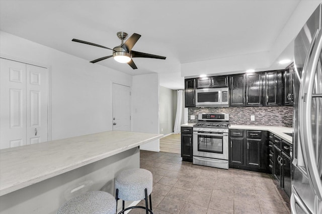 1903 Alton Dr, Champaign, IL 61821 - kitchen with stainless steel appliances, dark cabinetry, backsplash, a breakfast bar area, and ceiling fan