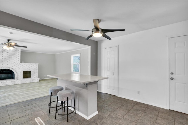 1903 Alton Dr, Champaign, IL 61821 - kitchen with ceiling fan, a breakfast bar area, a brick fireplace, a center island, and light countertops