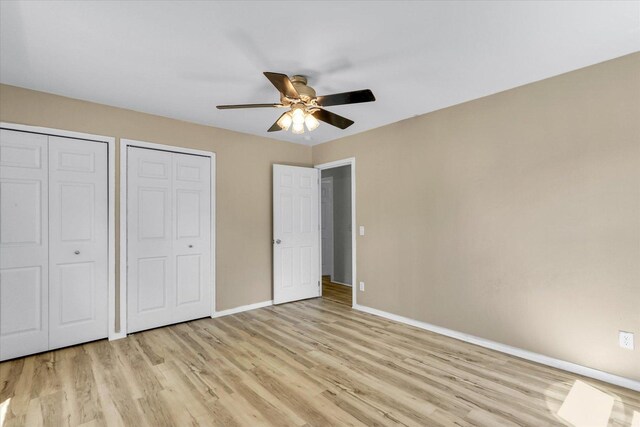 1903 Alton Dr, Champaign, IL 61821 - unfurnished bedroom with baseboards, two closets, light wood-style flooring, and ceiling fan