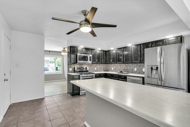 1903 Alton Dr, Champaign, IL 61821 - kitchen featuring stainless steel appliances, a sink, dark cabinetry, tasteful backsplash, and light countertops