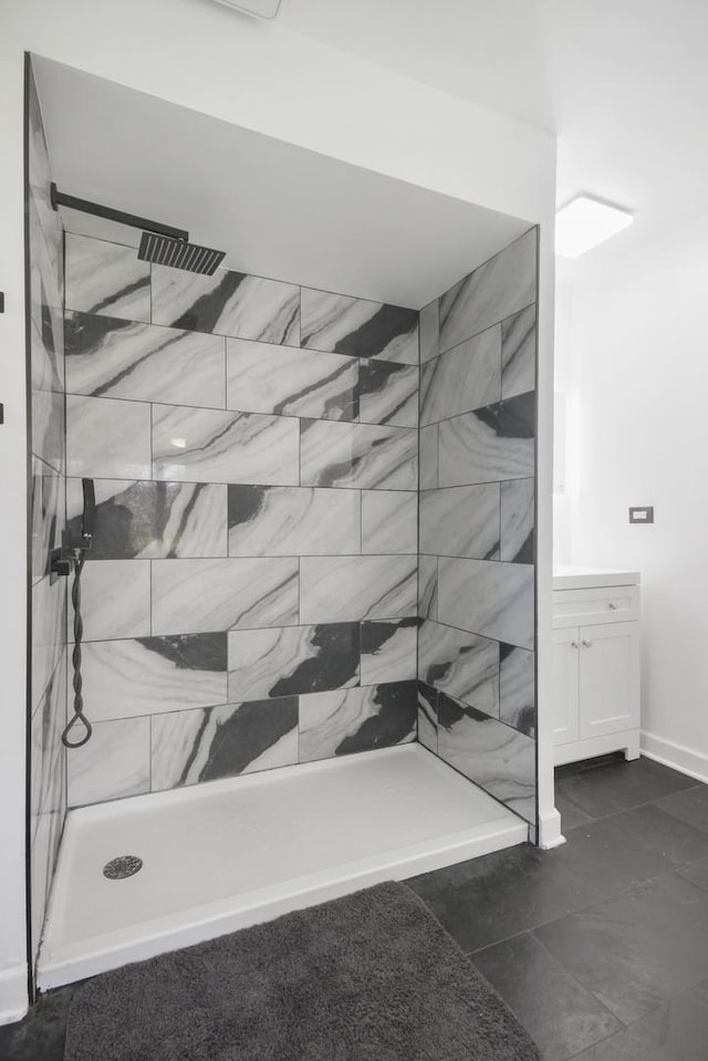 bathroom featuring tiled shower, vanity, and baseboards