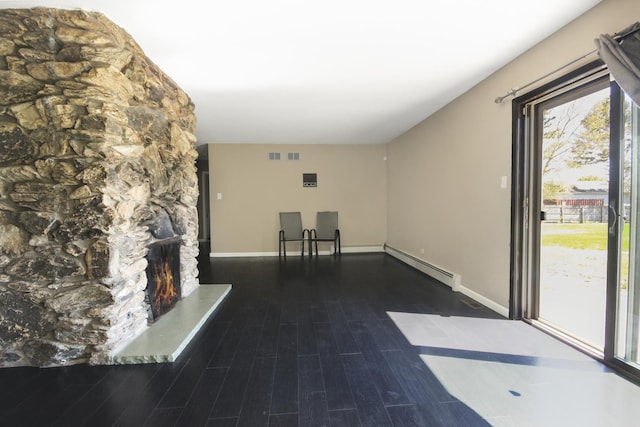 unfurnished living room with baseboard heating, wood finished floors, and baseboards