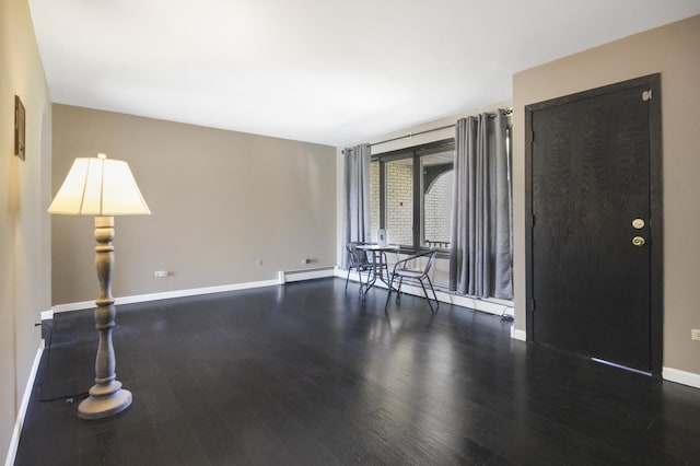 unfurnished room with a baseboard radiator, baseboards, and wood finished floors