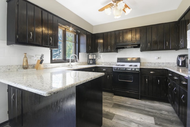 kitchen with range with gas cooktop, under cabinet range hood, a sink, a ceiling fan, and a peninsula