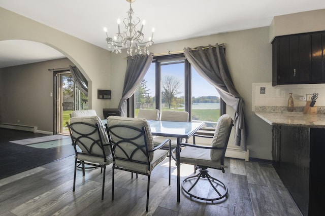 dining space featuring baseboard heating, arched walkways, plenty of natural light, and a chandelier