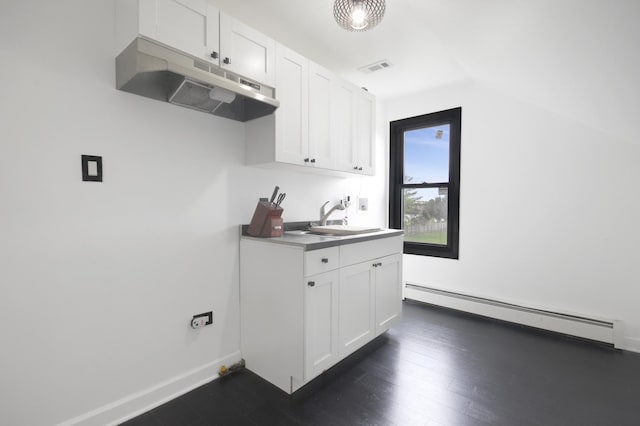 kitchen featuring under cabinet range hood, a baseboard radiator, a sink, white cabinetry, and baseboards