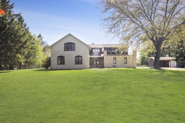 back of house featuring a lawn, brick siding, and an outbuilding