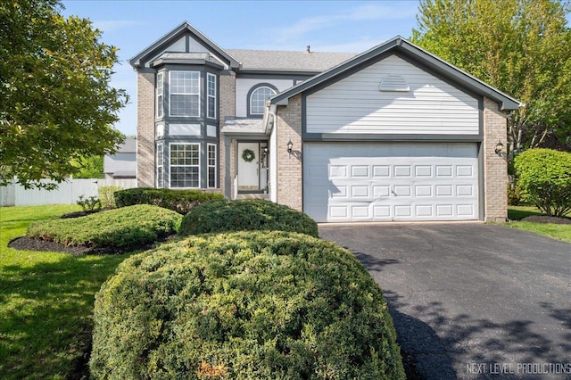 view of front of home with brick siding, asphalt driveway, a garage, and fence