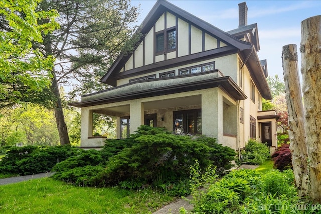 rear view of property with a chimney and stucco siding