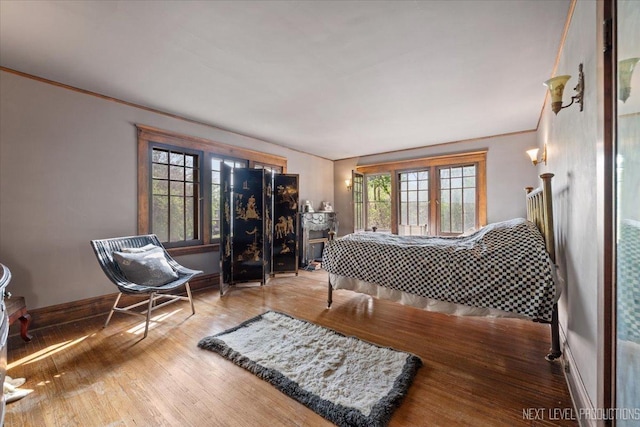 bedroom with wood finished floors, baseboards, and crown molding