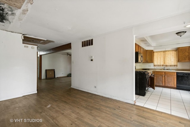 224 Shabbona Dr, Park Forest, IL 60466 - kitchen with black appliances, open floor plan, light wood-style flooring, brown cabinets, and light countertops