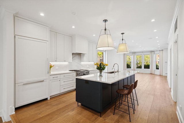 343 W Goethe St, Chicago, IL 60610 - kitchen featuring a sink, white cabinets, recessed lighting, light wood-style floors, and an island with sink