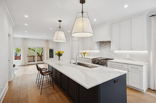 343 W Goethe St, Chicago, IL 60610 - kitchen with a sink, stainless steel gas range oven, white cabinets, tasteful backsplash, and light stone counters