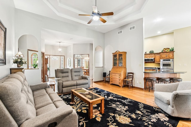 3840 W Nettle Creek Dr, Morris, IL 60450 - living room featuring a ceiling fan, light wood finished floors, a tray ceiling, recessed lighting, and arched walkways