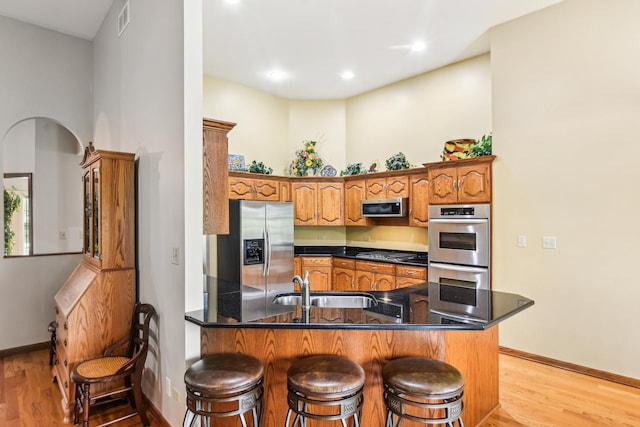 3840 W Nettle Creek Dr, Morris, IL 60450 - kitchen featuring stainless steel appliances, a peninsula, a sink, light wood-style flooring, and brown cabinets