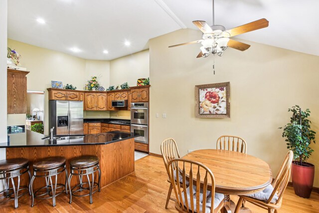 3840 W Nettle Creek Dr, Morris, IL 60450 - kitchen with appliances with stainless steel finishes, a peninsula, dark countertops, light wood finished floors, and a breakfast bar