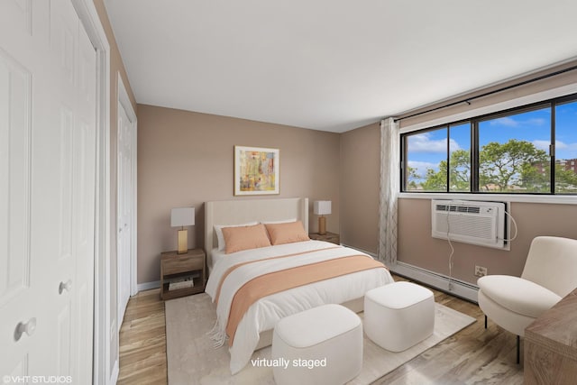 5327 N Delphia Ave Unit 327, Chicago, IL 60656 - bedroom with light wood-type flooring, a baseboard heating unit, a closet, and a wall mounted air conditioner