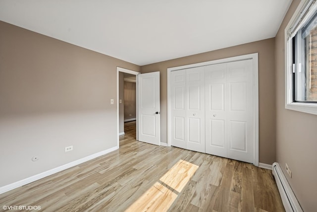 5327 N Delphia Ave Unit 327, Chicago, IL 60656 - unfurnished bedroom featuring a baseboard radiator, light wood-style floors, a closet, and a baseboard heating unit