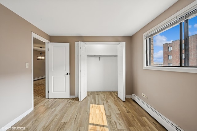 5327 N Delphia Ave Unit 327, Chicago, IL 60656 - unfurnished bedroom featuring baseboard heating, light wood-style floors, a baseboard heating unit, and a closet