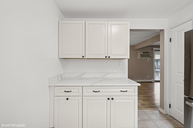 5327 N Delphia Ave Unit 327, Chicago, IL 60656 - kitchen featuring white cabinetry, a wall mounted AC, baseboard heating, light stone countertops, and refrigerator