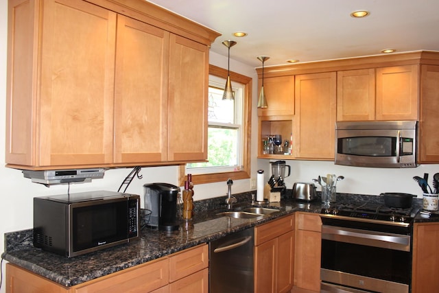 kitchen featuring appliances with stainless steel finishes, a sink, recessed lighting, decorative light fixtures, and dark stone counters