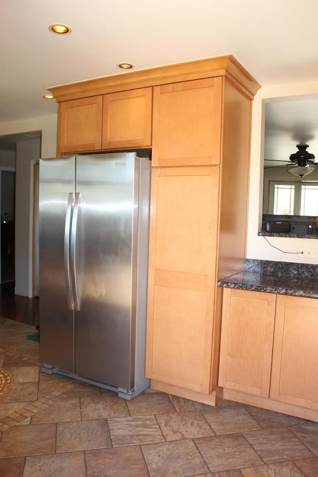 kitchen featuring freestanding refrigerator, stone finish flooring, dark stone counters, and recessed lighting