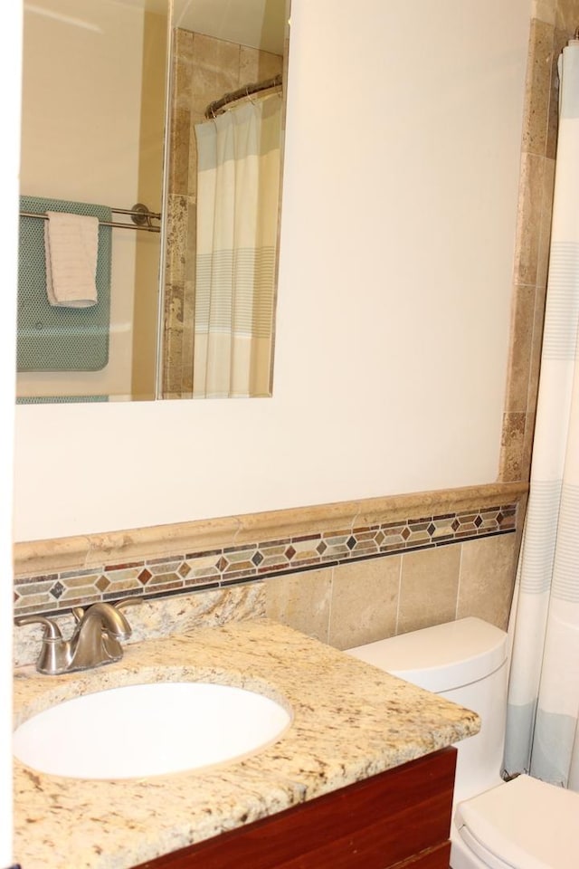 full bathroom featuring tile walls, vanity, wainscoting, toilet, and a shower with curtain