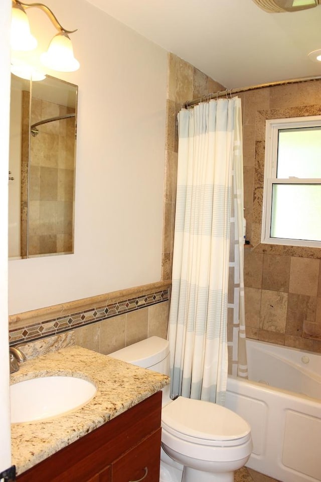bathroom with tile walls, shower / bath combination with curtain, vanity, and toilet