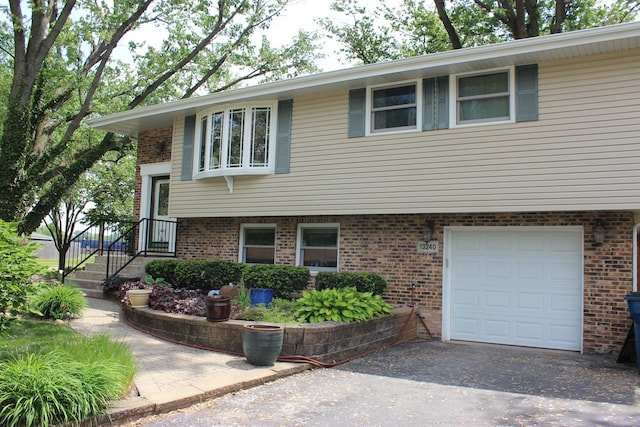 raised ranch with a garage, brick siding, and driveway