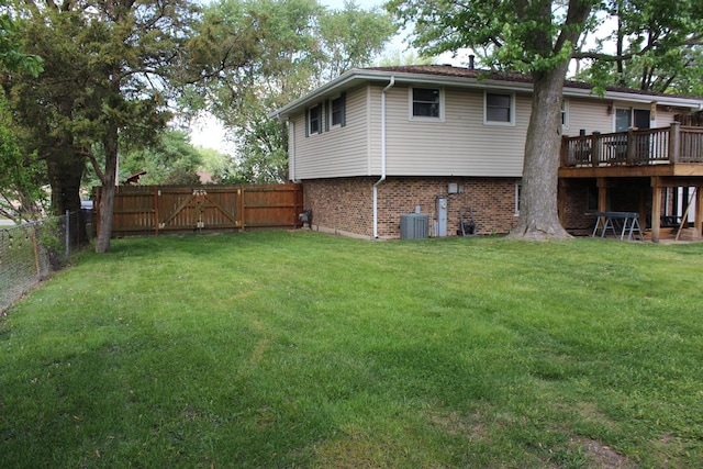 back of house featuring brick siding, a deck, cooling unit, and a gate