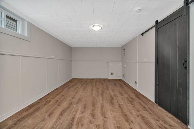 3811 N Pioneer Ave, Chicago, IL 60634 - basement with a barn door, light wood-style flooring, a decorative wall, and ornamental molding