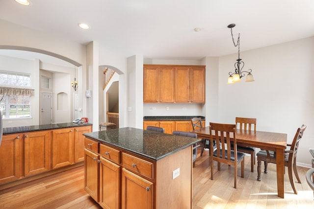 921 Winners Cup Ct, Naperville, IL 60565 - kitchen with arched walkways, light wood-style floors, brown cabinets, pendant lighting, and dark stone countertops