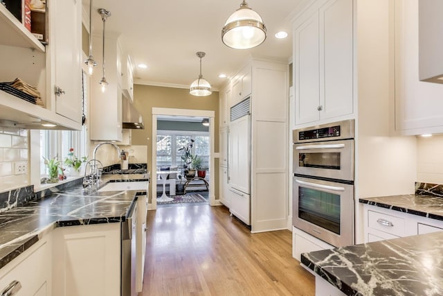 518 Clarence Ave, Oak Park, IL 60304 - kitchen featuring appliances with stainless steel finishes, white cabinets, backsplash, wall chimney exhaust hood, and light wood finished floors