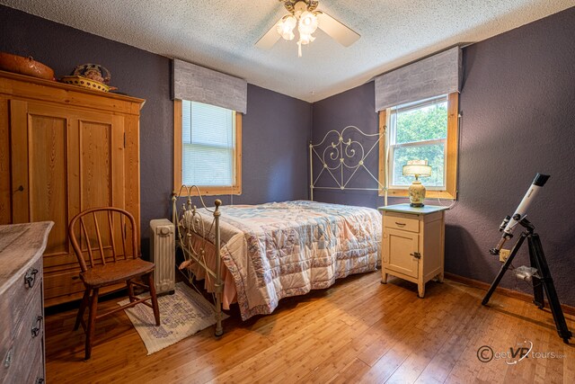 5567 N Mill Creek Rd, Scales Mound, IL 61075 - bedroom featuring a textured wall, light wood finished floors, radiator heating unit, a textured ceiling, and ceiling fan