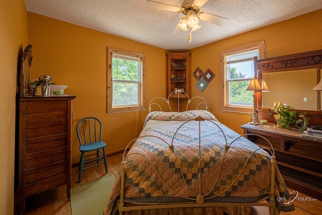 5567 N Mill Creek Rd, Scales Mound, IL 61075 - bedroom featuring a textured wall, a textured ceiling, multiple windows, wood finished floors, and ceiling fan