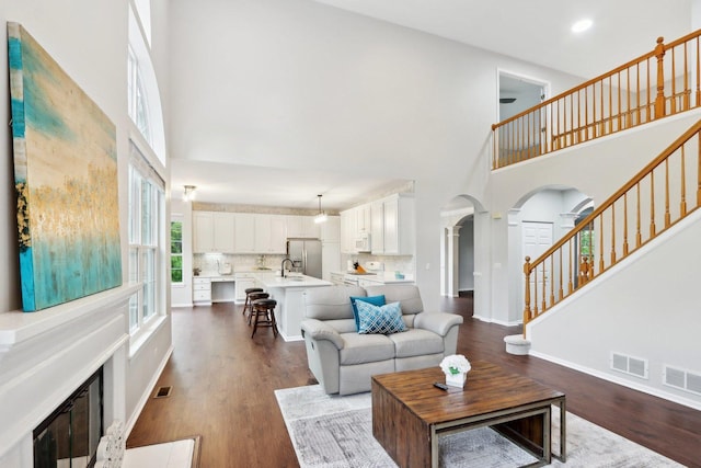 2913 Glenarye Dr, Lindenhurst, IL 60046 - living room with arched walkways, a high ceiling, dark wood-style floors, stairs, and baseboards