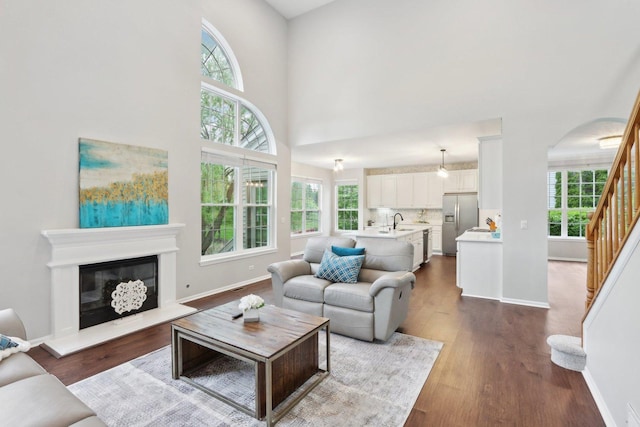 2913 Glenarye Dr, Lindenhurst, IL 60046 - living room with stairs, dark wood-style flooring, a towering ceiling, baseboards, and a glass covered fireplace