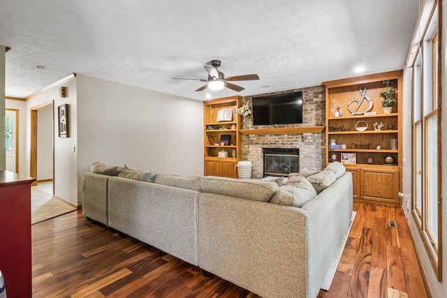 2610 Worthington Dr, Champaign, IL 61822 - living room featuring ceiling fan, a brick fireplace, wood-type flooring, a textured ceiling, and baseboards