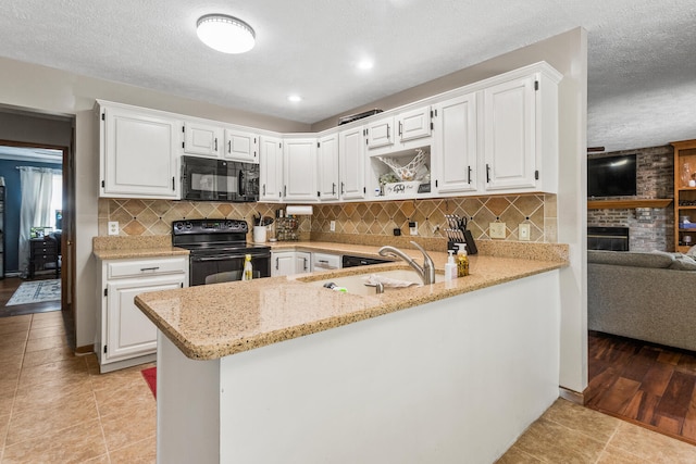 2610 Worthington Dr, Champaign, IL 61822 - kitchen with black appliances, light stone countertops, white cabinetry, a peninsula, and a textured ceiling