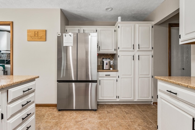 2610 Worthington Dr, Champaign, IL 61822 - kitchen with freestanding refrigerator, white cabinetry, light stone countertops, light tile patterned floors, and a textured ceiling