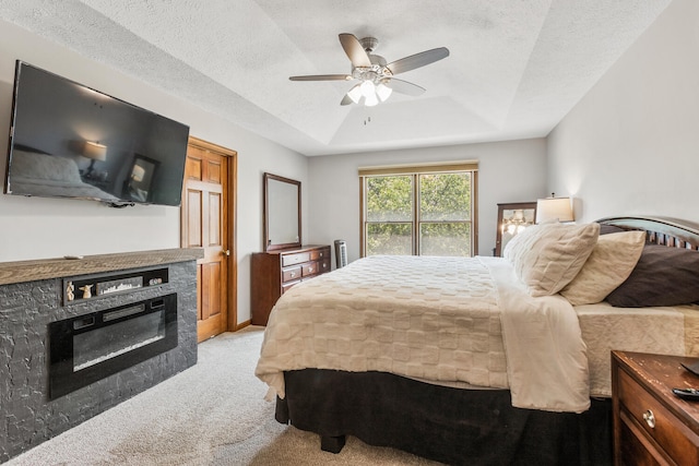 2610 Worthington Dr, Champaign, IL 61822 - bedroom with light colored carpet, a tray ceiling, a glass covered fireplace, a textured ceiling, and ceiling fan